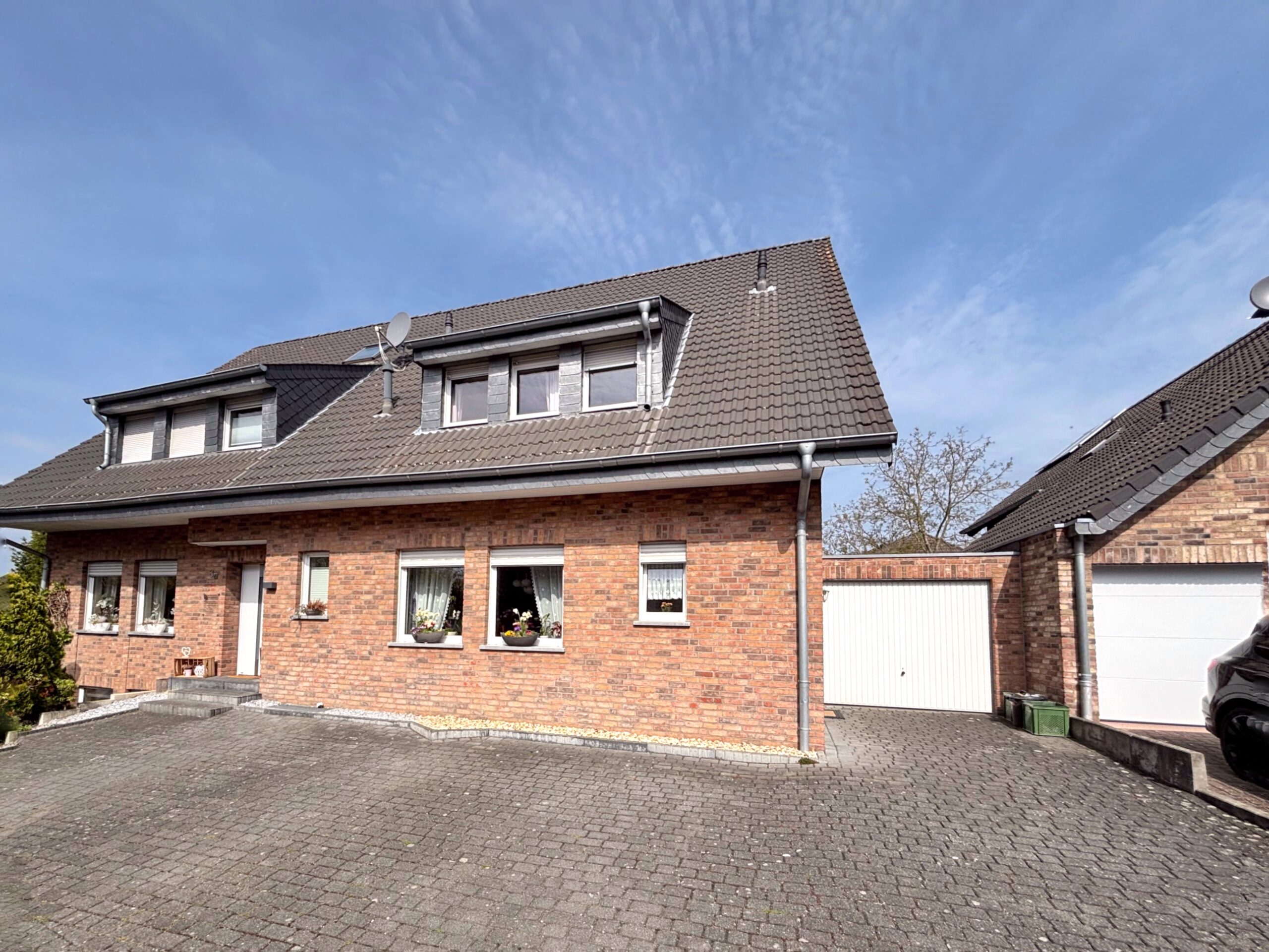 Das Bild zeigt die Außenansicht einer Doppelhaushälfte mit Garage.