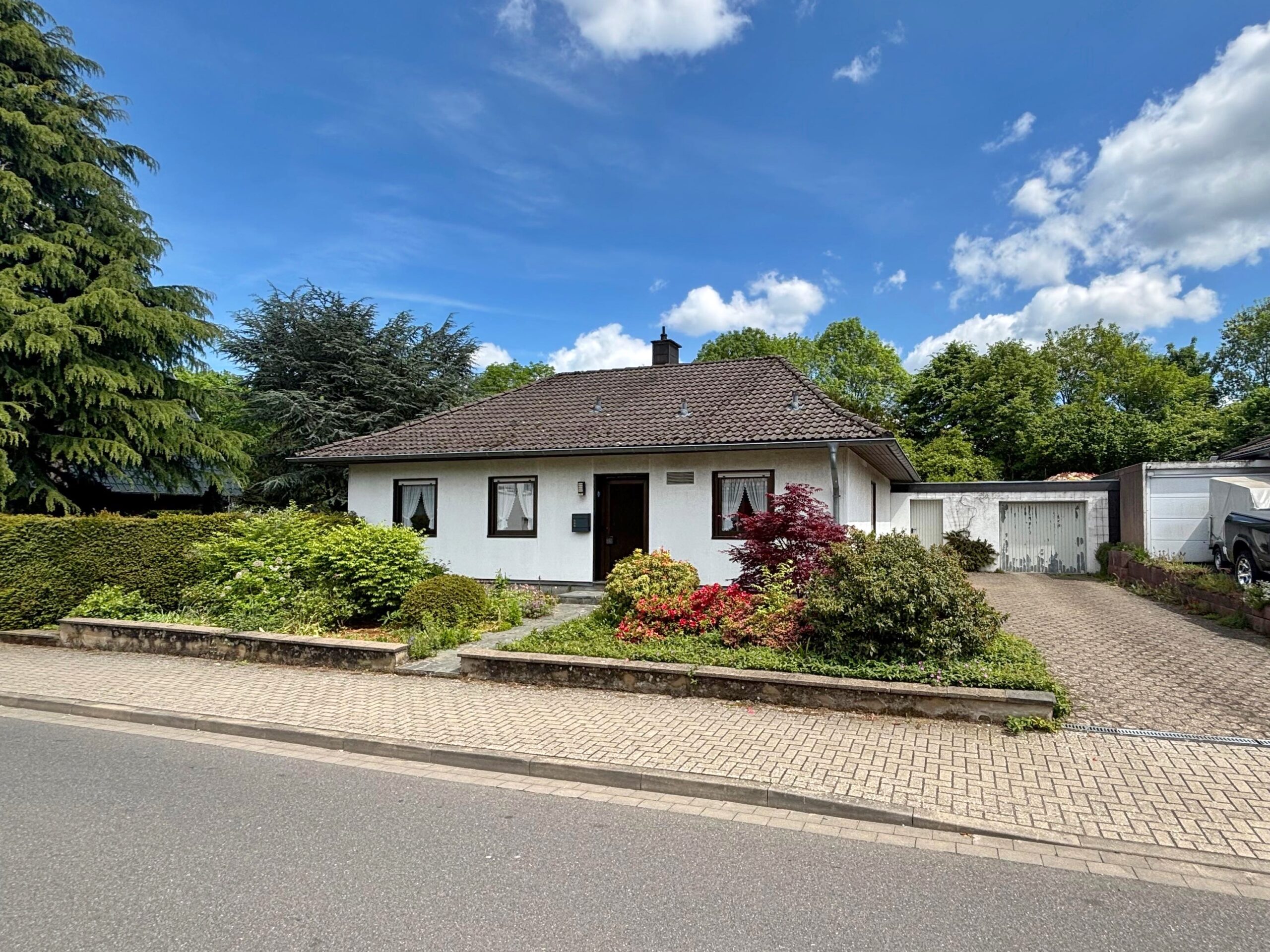 Das Bild zeigt die Außenansicht des Bungalows mit Einfahrt zur Garage.