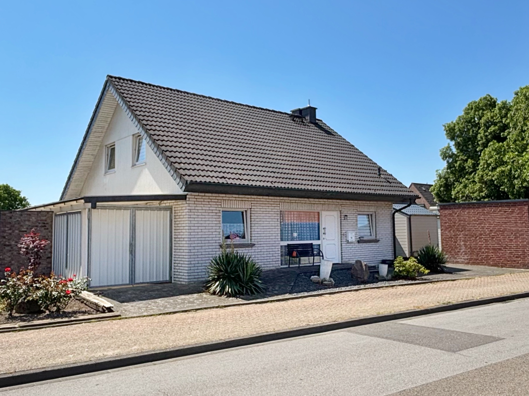 Das Bild zeigt die Außenansicht eines weiß verklinkerten Einfamilienhause.