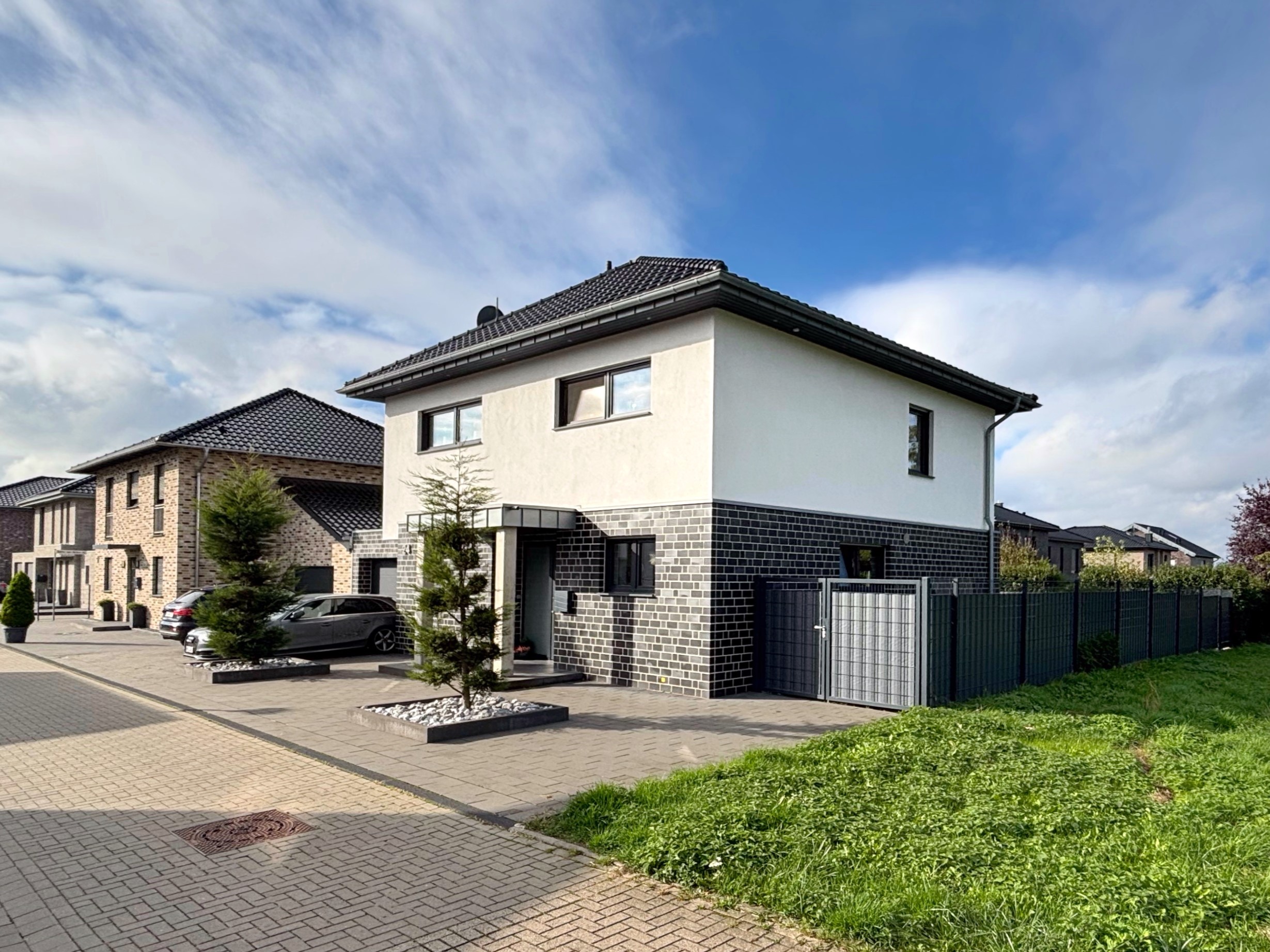 Das Bild zeigt ein Einfamilienhaus. Der obere Bereich ist weiß verputzt, der untere Bereich verklinkert.