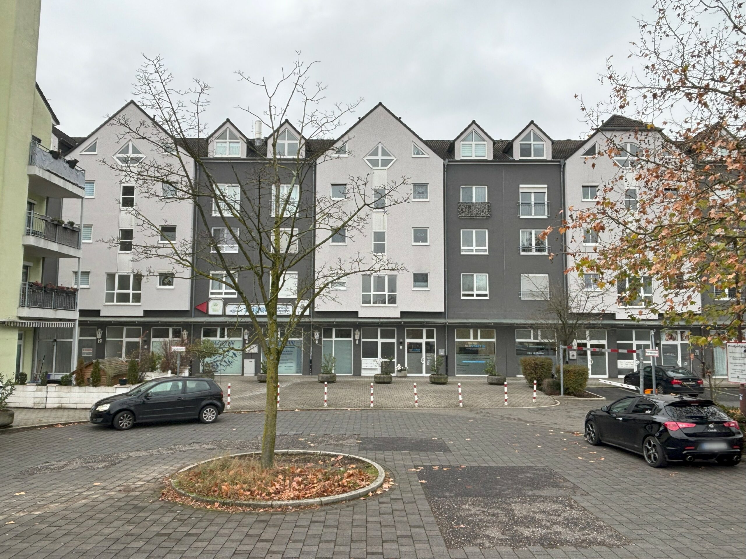 Das Bild zeigt die Außenansicht eines gepflegten Wohn- und Geschäftshauses, eingerahmt von weiteren Häusern.
