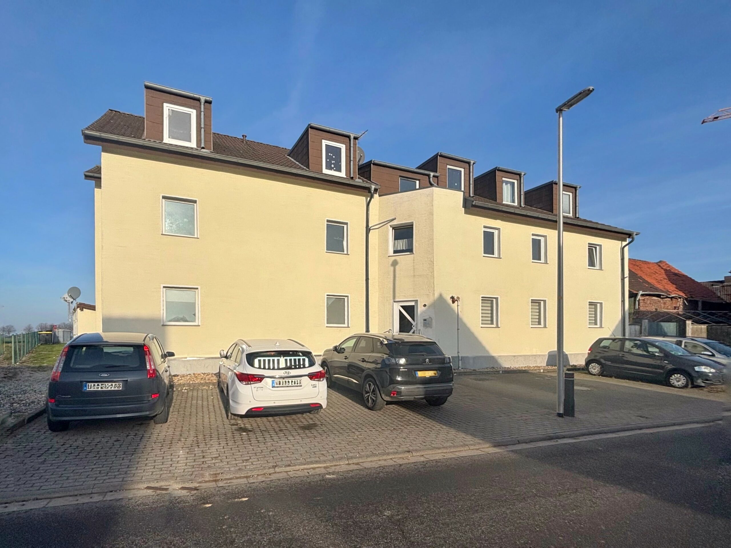 Das Bild zeigt die Außenansicht eines gelb verputzten Mehrfamilienhauses in der sich die Wohnung befindet.