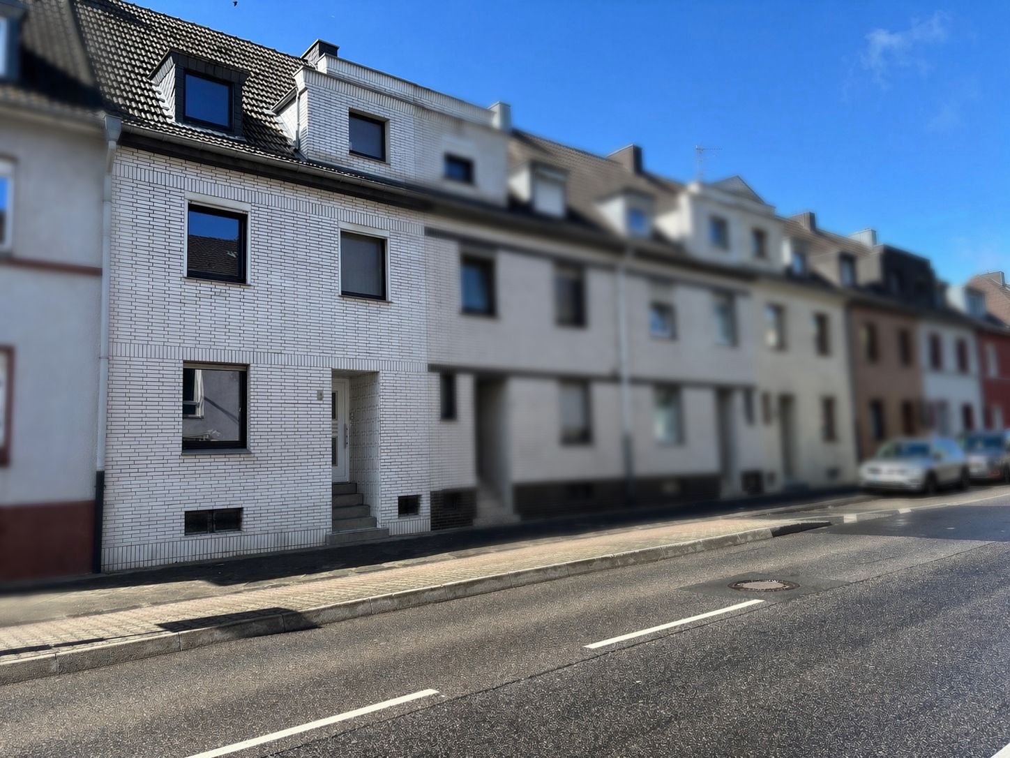 Das Bild zeigt die Außenansicht eines weiß geklinkerten Reihenmittelhauses.