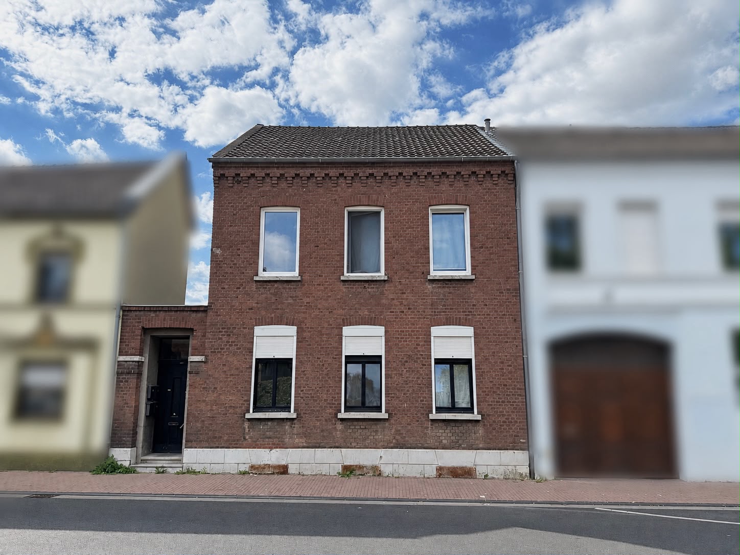 Das Foto zeigt die Frontansicht eines verklinkertes Reihenmittelhaus mit sechs Fenstern.