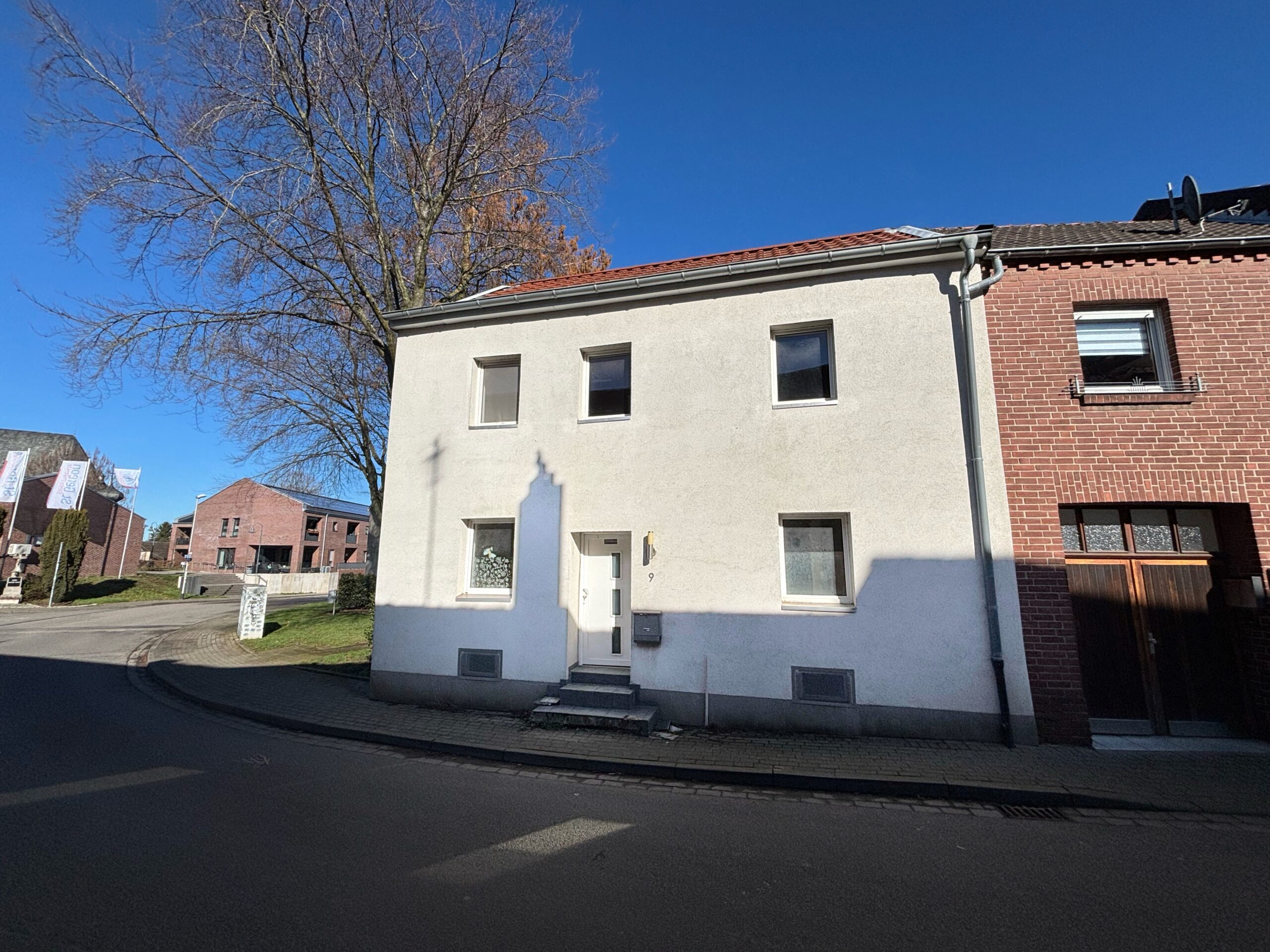 Das Bild zeigt die Außenansicht eines weiß verputzten Einfamilienhauses.