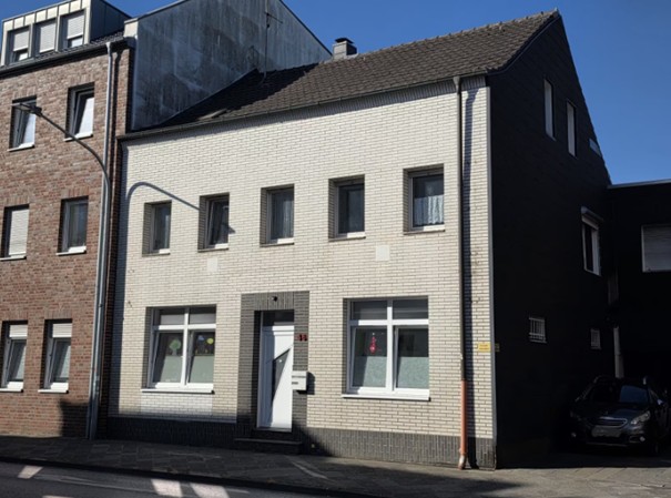 Das Bild zeigt die Außenansicht eines weiß geklinkerten Zweifamilienhauses.